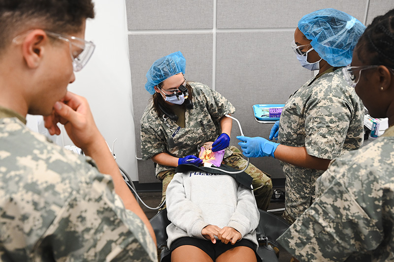 Military Dentist with a patient and an assistant inside a military tent